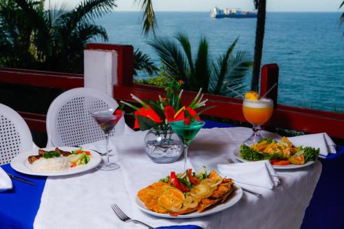 a table with plates of food and a view of the ocean at Hotel Maribu Caribe in Puerto Limón