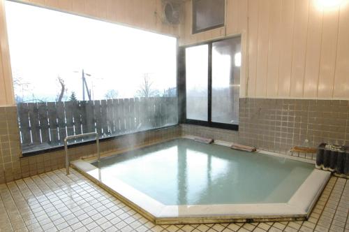 Un gran charco de agua en una habitación con ventana. en Tazawa Kogen Hotel, en Senboku