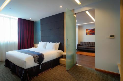 コタキナバルにあるThe Klagan @ Riverson Hotelのベッドとソファ付きのホテルルーム