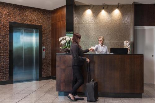 a woman is standing at a counter in a lobby at Springfield Lakes Boutique Hotel in Springfield Lakes