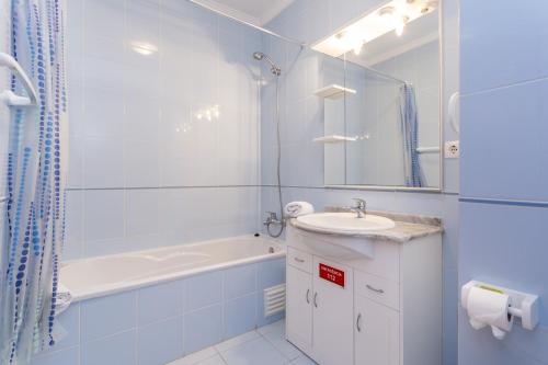 uma casa de banho com uma banheira, um lavatório e uma banheira tubermott em Apartamento Tatiana em Portimão