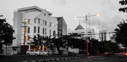 a city with cars parked in front of a building at DeMira Hotel in Surabaya