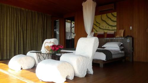a bedroom with a bed with white chairs and a table at Aythaya Monte diVino Lodge in Taunggyi