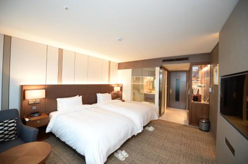 a bedroom with a large white bed and a television at Hotel Interburgo Daegu in Daegu