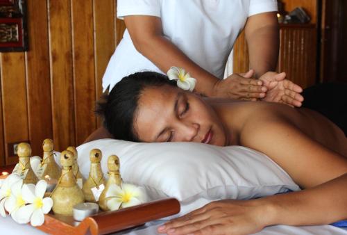 a woman laying on a bed getting a massage at Gangga Island Resort & Spa in Serai