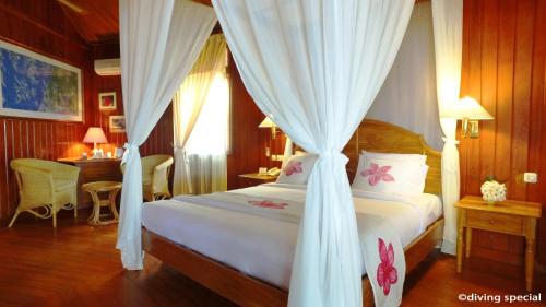 a bedroom with a white canopy bed with curtains at Gangga Island Resort & Spa in Serai