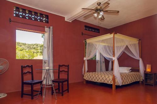 a bedroom with a canopy bed and two chairs at Hotel Nautile in Sainte Marie