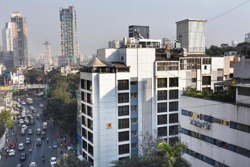 een hoog wit gebouw naast een straat met auto's bij The Shalimar Hotel, Kemps Corner in Mumbai