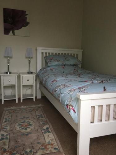 a bedroom with a white bed and two night stands at Fir Tree Cottage in Chester