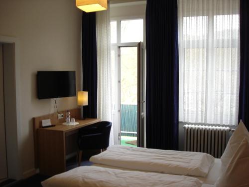 アンダーナッハにあるRhein-Hotelのベッド、デスク、窓が備わるホテルルームです。