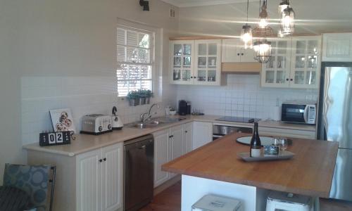 a kitchen with white cabinets and a wooden counter top at Casa Rossa - Barossa in Lyndoch