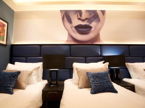 two beds in a hotel room with a picture of a woman at The Residence Hotel in Galway