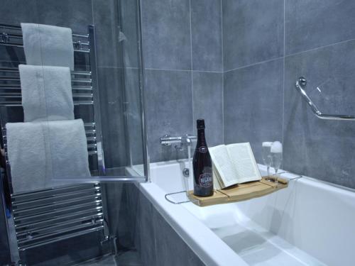 a bathroom with a bottle of beer and a book on a bath tub at The Residence Hotel in Galway