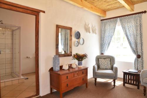 - un salon avec une chaise, une table et un miroir dans l'établissement De Hoop Collection Suites, à De Hoop Nature Reserve