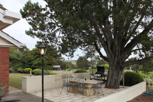 a patio with a table and chairs under a tree at Casa Rossa - Barossa in Lyndoch