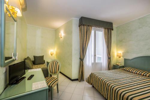 a hotel room with two beds and a desk at Hotel Riviera 3 Stelle con piscina estiva gratuita e garage a pagamento in Spotorno