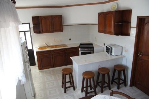 una cocina con armarios de madera y taburetes de bar. en Apartamentos Atalaia, en Sagres