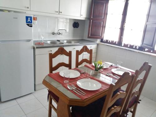 ヴィラ・ノヴァ・デ・ミルフォンテスにあるApartamento T2 Pintassilgoのキッチン(テーブル、椅子、冷蔵庫付)