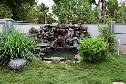 a pond in a yard with a stone waterfall at Srinikethana Home Stay with Swimming Pool in Madikeri