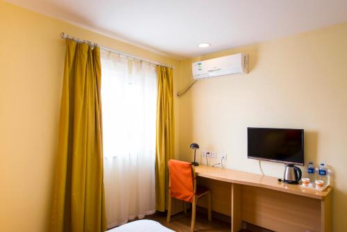 a room with a desk with a television and a window at Home Inn Dalian Development Zone Light Railway Station in Jinzhou