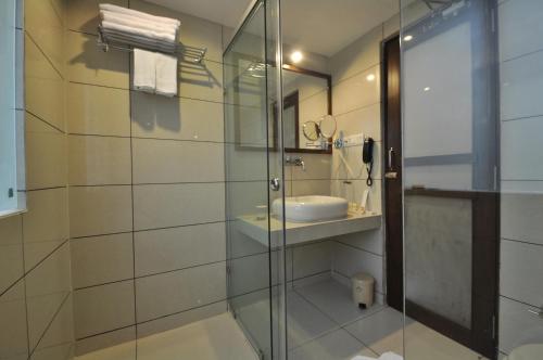 uma casa de banho com uma cabina de duche em vidro e um lavatório. em Le Grande Residency em Ahmedabad
