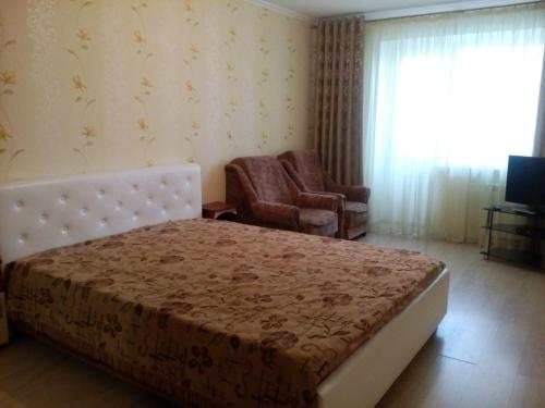 um quarto com uma cama, uma cadeira e uma janela em Apartment on Lenina 73 em Kaluga