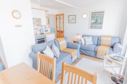 a living room with a blue couch and a table at Tolcarne Beach Apartments in Newquay