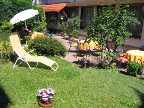 einen Garten mit Stühlen, Tischen und einem Sonnenschirm in der Unterkunft Hotel Stadtschänke in Bad König