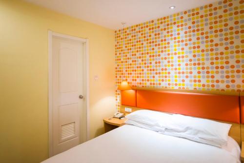 a bedroom with an orange headboard and a white bed at Home Inn Yuncheng Yuxi Road Yudu in Yuncheng
