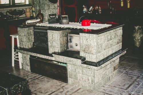 a brick fireplace in a living room with a red appliance at Pousada Rural Casa de Pedra in Urubici