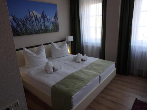 a bedroom with a white bed with towels on it at Garni Hotel Lavendelhof in Nauen