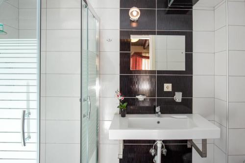 biała łazienka z umywalką i lustrem w obiekcie Casa Di Porto w Chanii