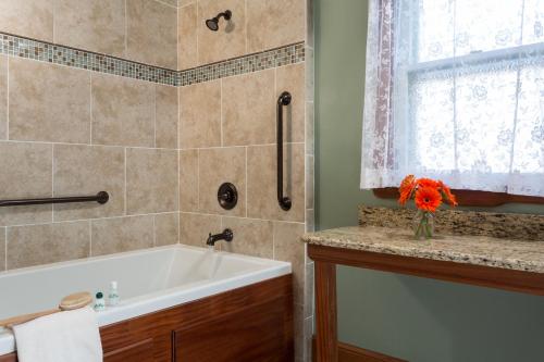 a bathroom with a tub and a sink and a window at The Queen Victoria in Cape May