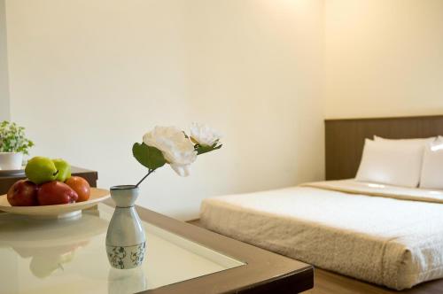 a vase with a flower on a table in a bedroom at Good Ground Hotel Tainan in Tainan
