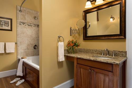 a bathroom with a sink and a tub and a mirror at The Queen Victoria in Cape May