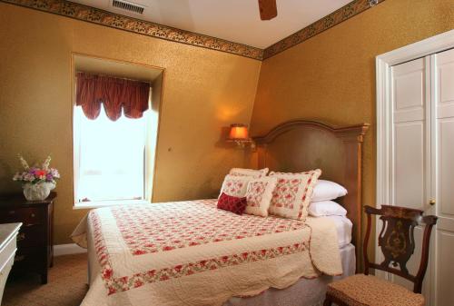a bedroom with a bed with pillows and a window at The Queen Victoria in Cape May