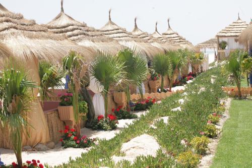 a row of umbrellas in a garden with flowers at Alhambra Thalasso in Hammamet