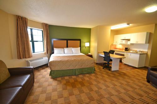 ein Hotelzimmer mit einem Bett und einem Schreibtisch in der Unterkunft Suburban Studios in Auburn Hills