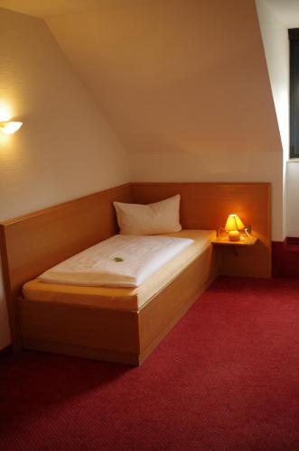 a small bedroom with a bed with a lamp on it at Hotel Zum Abschlepphof in Leipzig