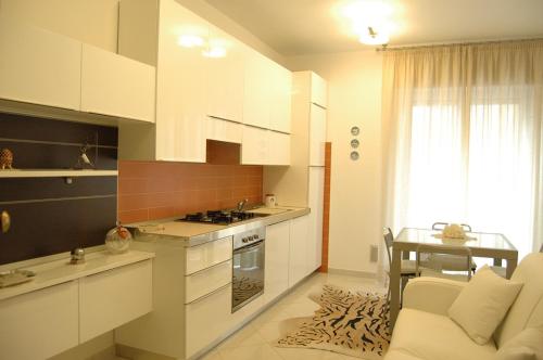 a kitchen with white cabinets and a table and a couch at Apartment Serena in Alassio