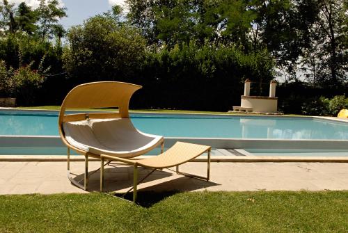 a chair sitting in the grass next to a swimming pool at Agrisalotto in Cortona