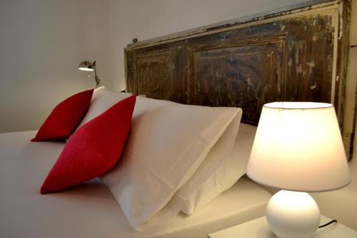 a bed with red and white pillows next to a lamp at La Gazza Ladra Apartments - Garda Chill Out in Drena