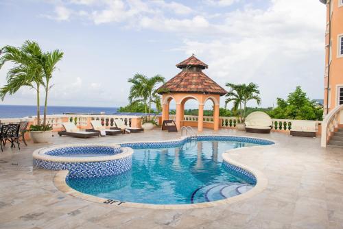een zwembad met een prieel en de oceaan bij Villa Sweet Villa - Montego Bay in Montego Bay