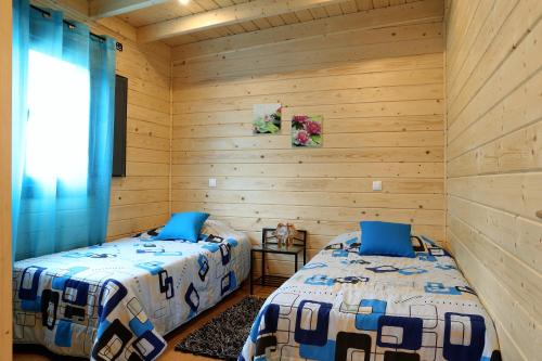 Duas camas num quarto com paredes de madeira em Zona Balnear do Meimao em Meimão