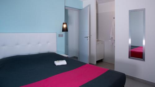 een slaapkamer met een zwart en roze bed en een spiegel bij Résidence Coté Mer in La Grande-Motte