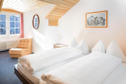 a bedroom with two beds and a chair at Berghaus Männlichen in Grindelwald