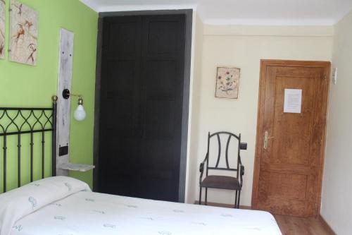 a bedroom with a black door and a chair at Hostal-Restaurante Fogón de Gredos in Guisando