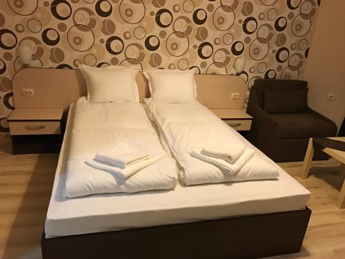 a bed with a white comforter and pillows at Hotel Body M in Vratsa