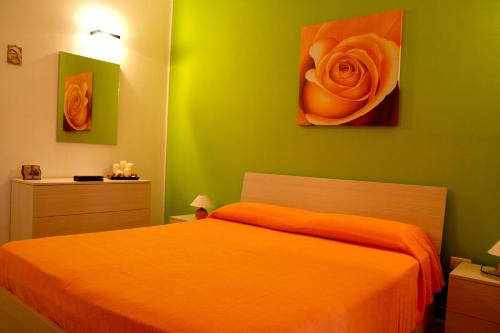 オートラントにあるAppartamento Gioveのベッドルーム1室(オレンジ色のベッド1台、バラの絵画付)