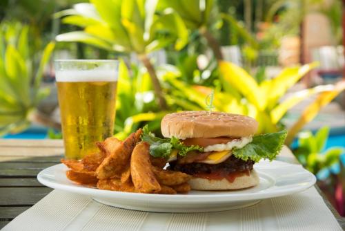 a plate with a burger and fries and a glass of beer at Hotel Casa Turire in Turrialba